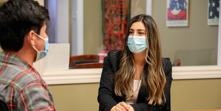 A female student is seated at a desk while wearing a mask