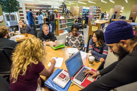 A group of law students gather at a library table.