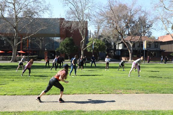 A woman leads a Zumba class on the quad