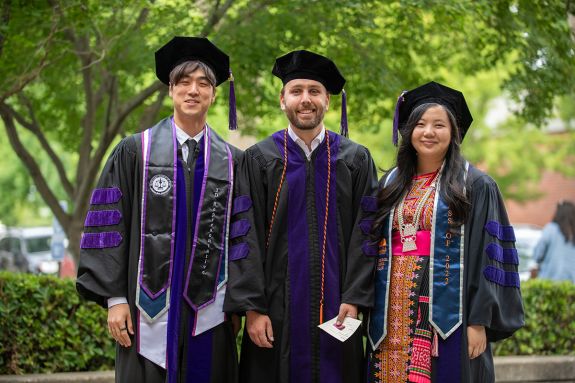 Three graduates wearing graduation regalia 