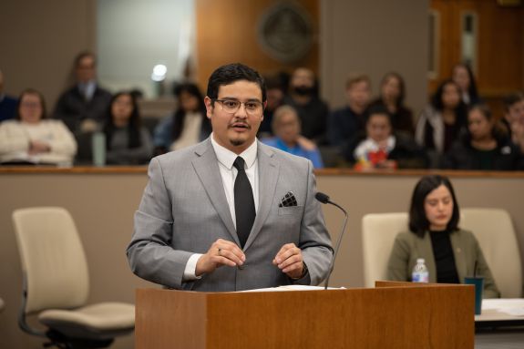Man in grey suit speaks at a podium