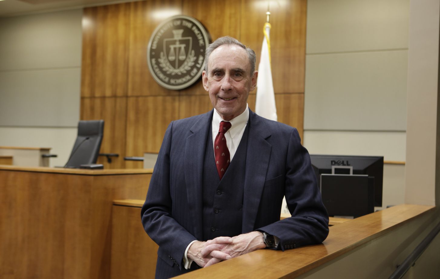 A man in a suit poses for a photo in a courtroom.