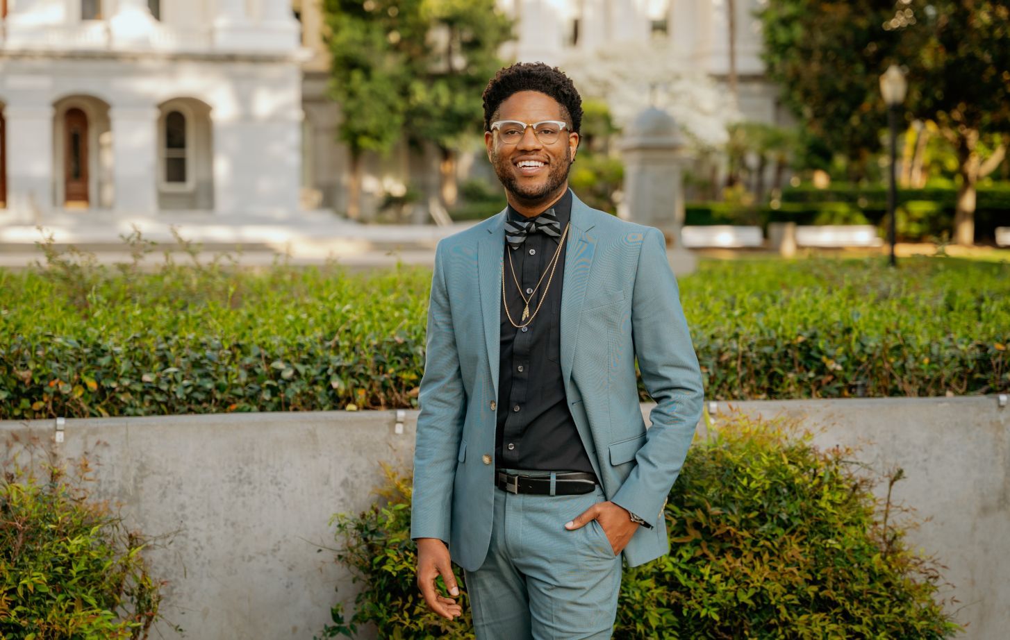 A Black man standing outside the California State Capitol Building, smiling.