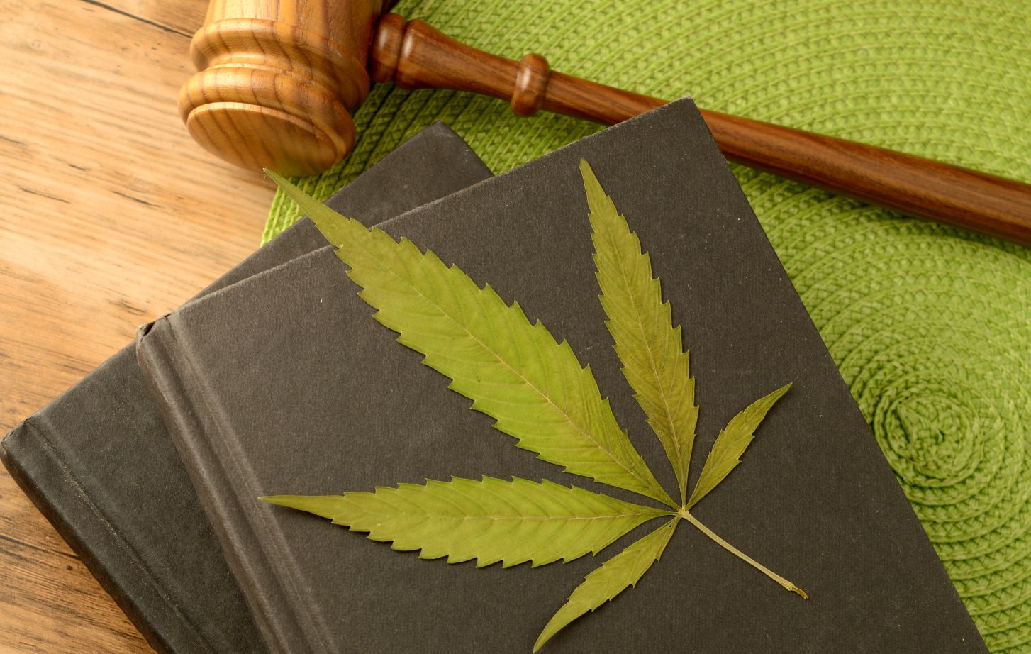 A conceptual image focused on the legal information of Marijuana using books and a gavel and weed leaf to illustrate this idea.