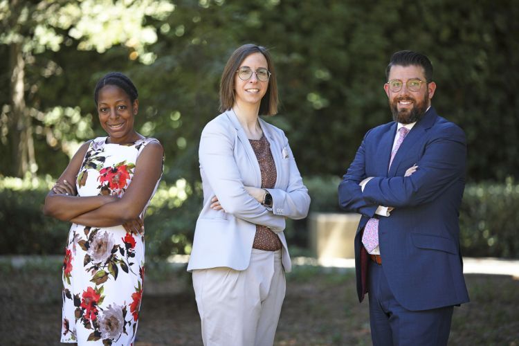 Three law professors pose for a photo in front of a green background.