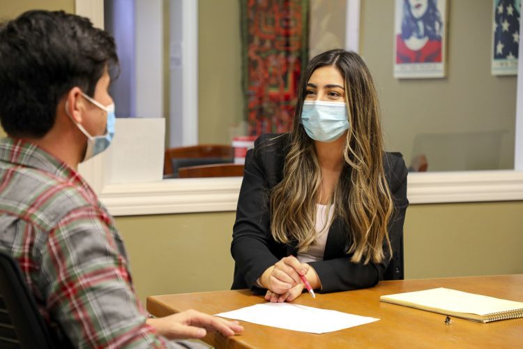 Third-year law student Flora Feizi looks at a client while conducting a meeting in the school's legal clinics. Both individuals are seated. 