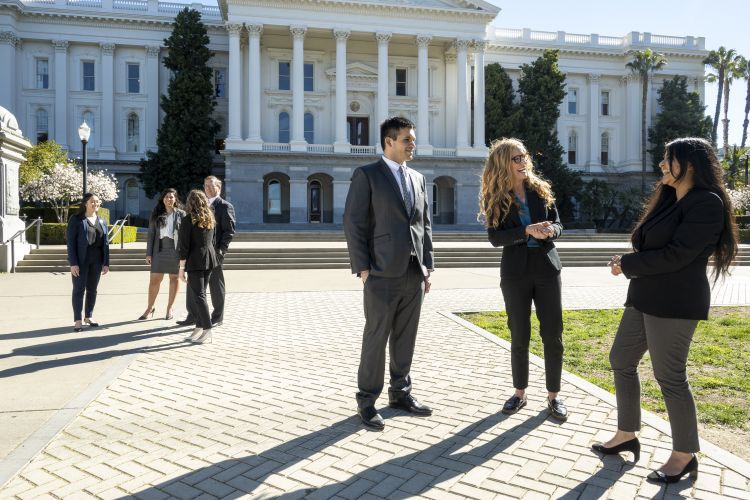 Professors Erin O'Neal Muilenburg and Chris Micheli are pictured with a group of law students in front of the California State Capitol Building in Sacramento, California.  