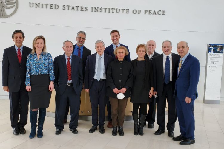 11 people pose for a photo under a sign that says U.S. Institute of Peace