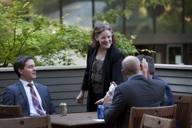 A standing woman talks to three seated students