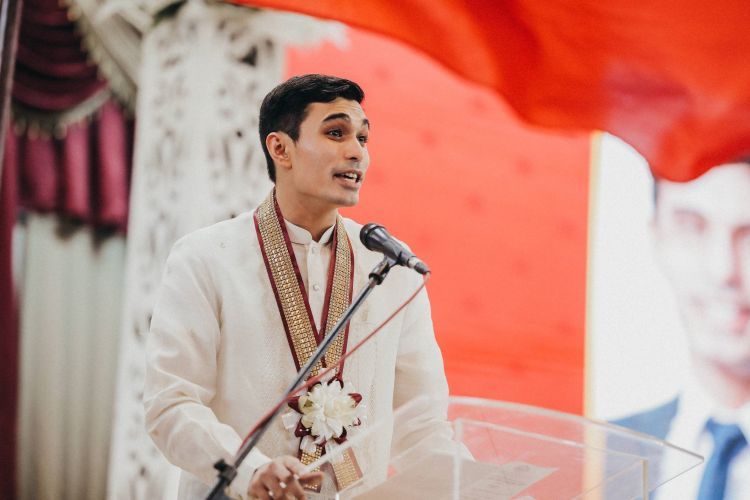 A man in traditional Pilipino attire speaks at a podium 