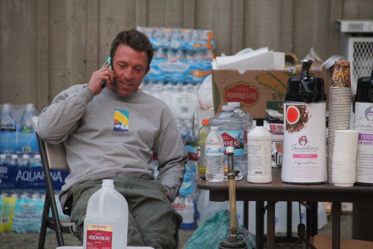 A man talking on the phone sits next to natural diaster relief supplies