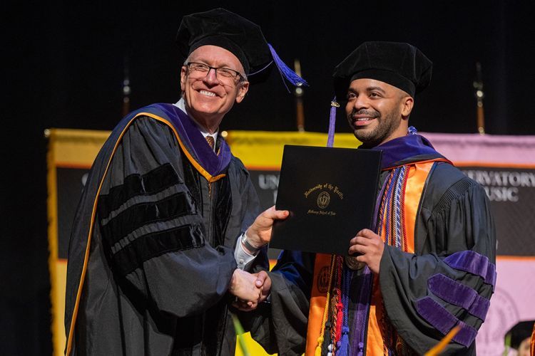 A student and law dean pose on graduation.