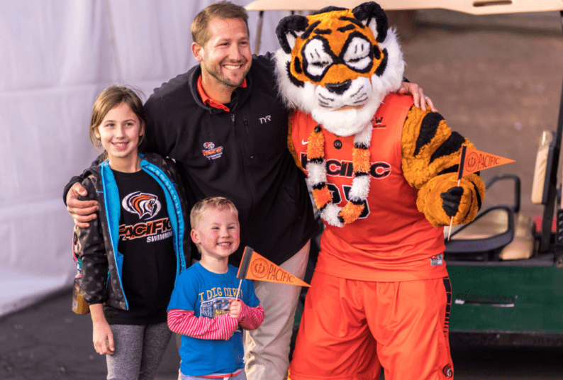 the powercat mascot poses for a picture with a man and two children