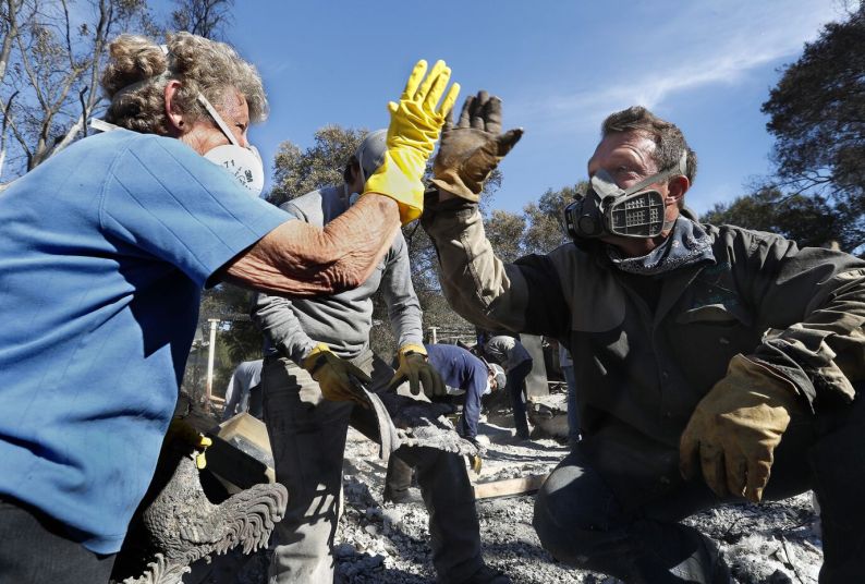 Two people wearing protective gear high-five each other