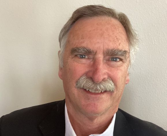 A man wearing a suit smiles for a photo