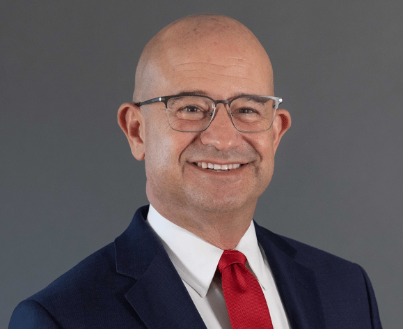 A man wearing a suit smiles for a photo 