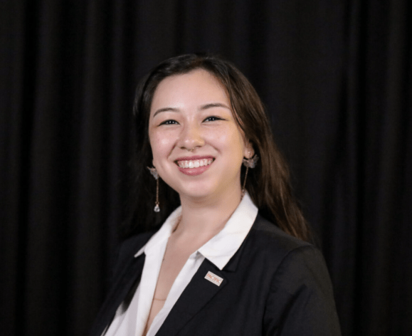A portrait of a woman wearing a suit in front of a black background